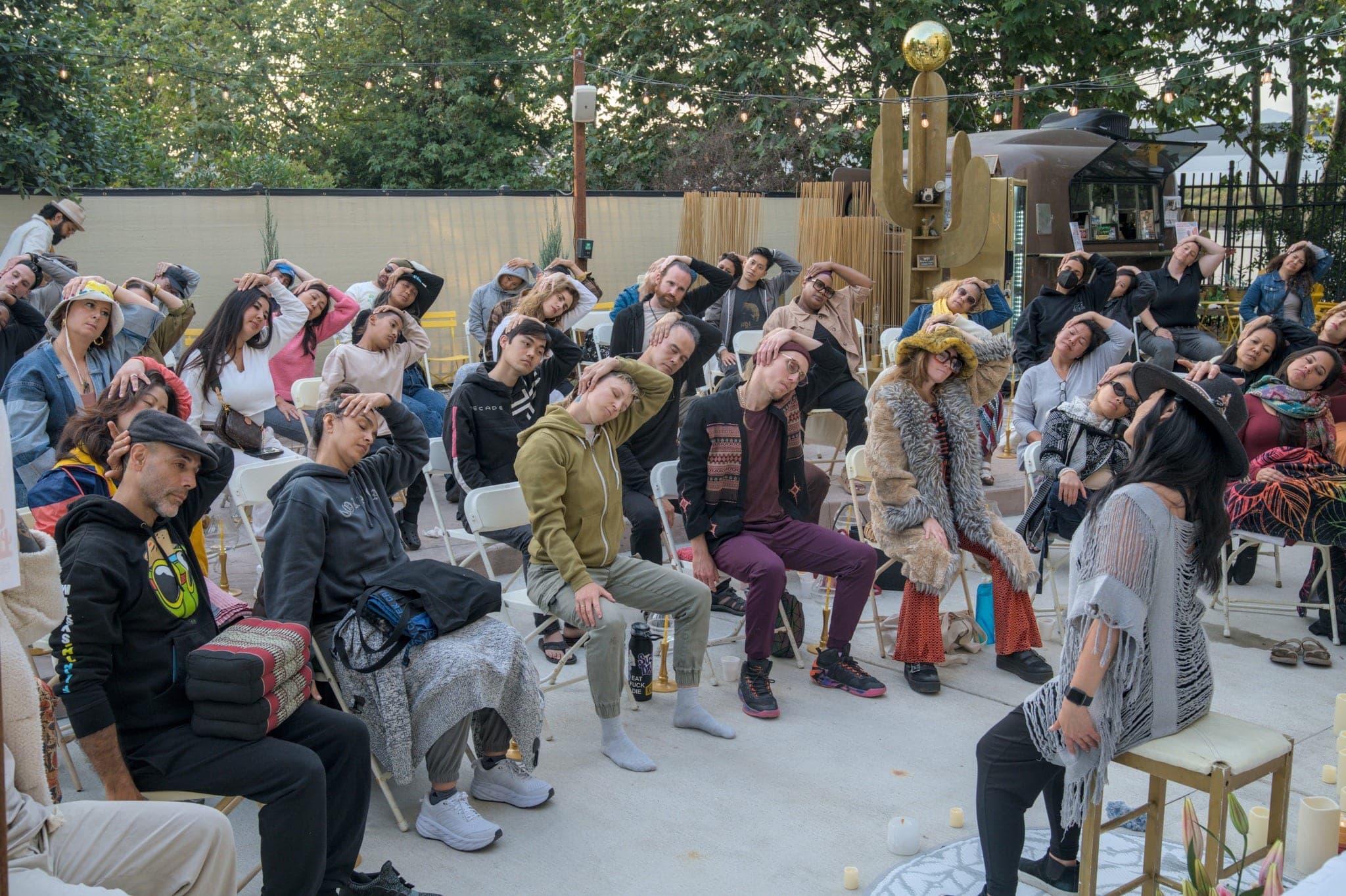Guests seated outdoors in a garden courtyard, listening.