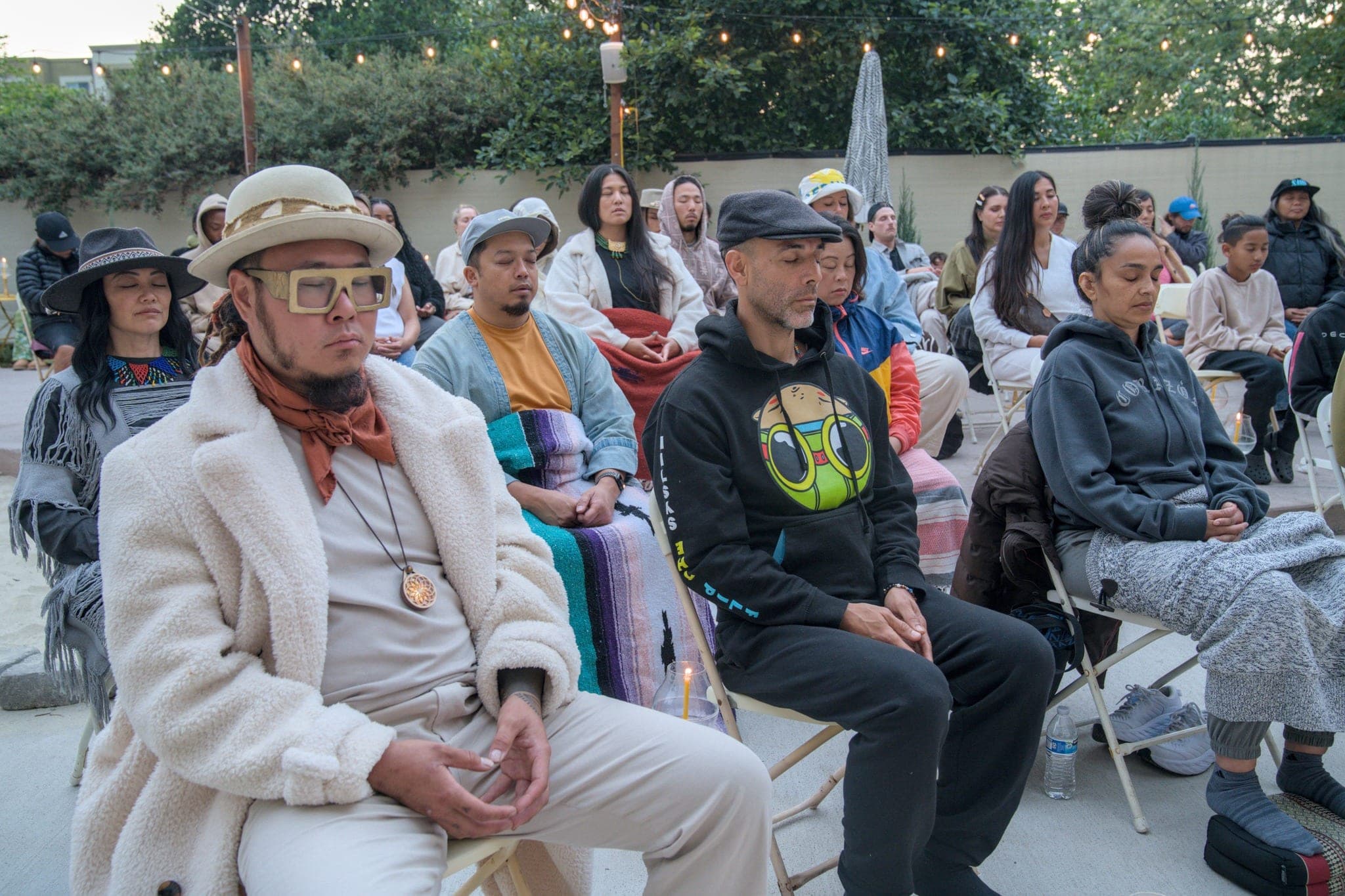 Guests seated in a garden courtyard under strung lights.