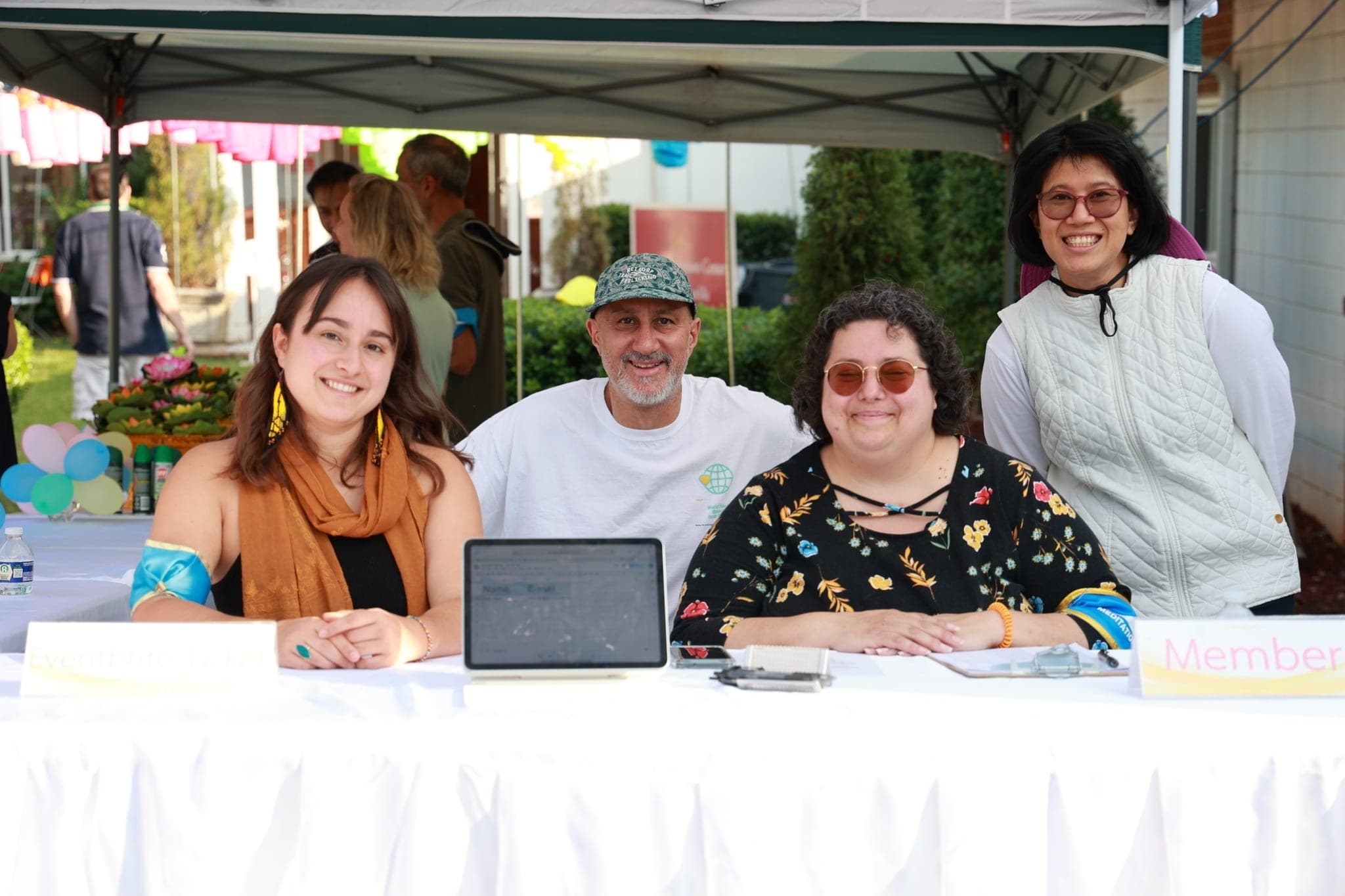 Volunteers at a welcome table under a canopy.