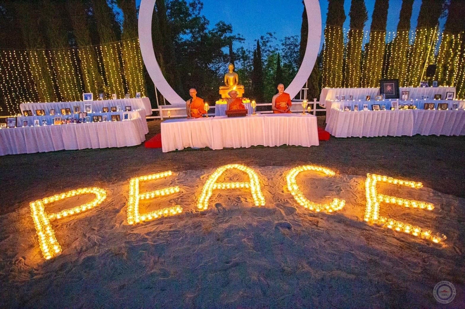 The word PEACE spelled out in candles on the ground before a lit archway and an altar.