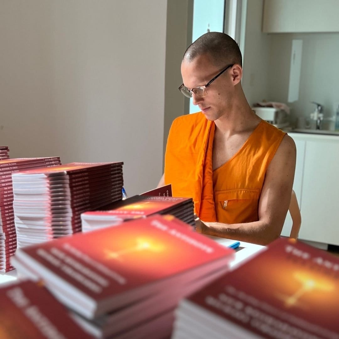 A monk reading beside stacks of freshly printed books.