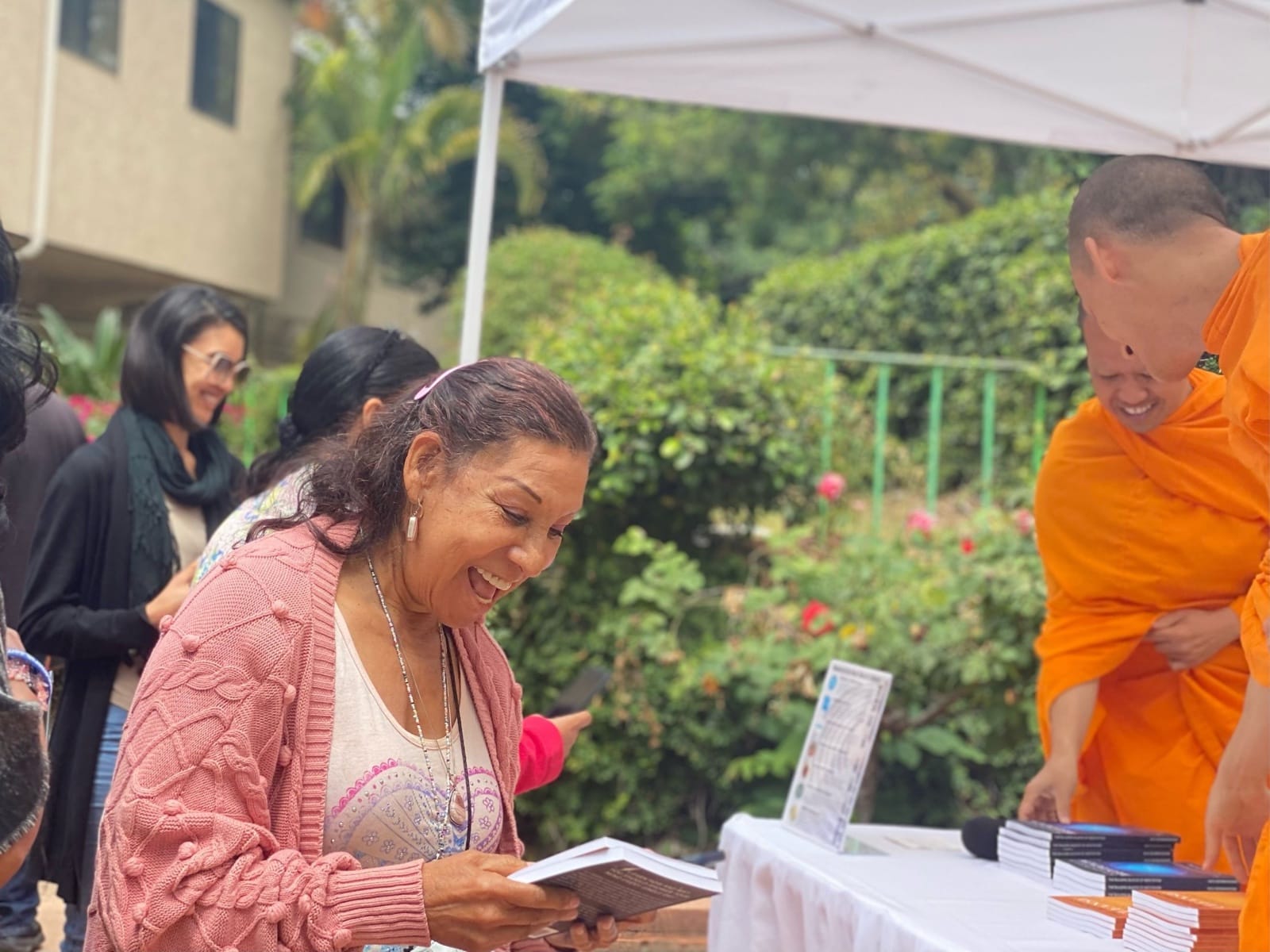 A visitor looking through a book handed out by a monk at an outdoor table.