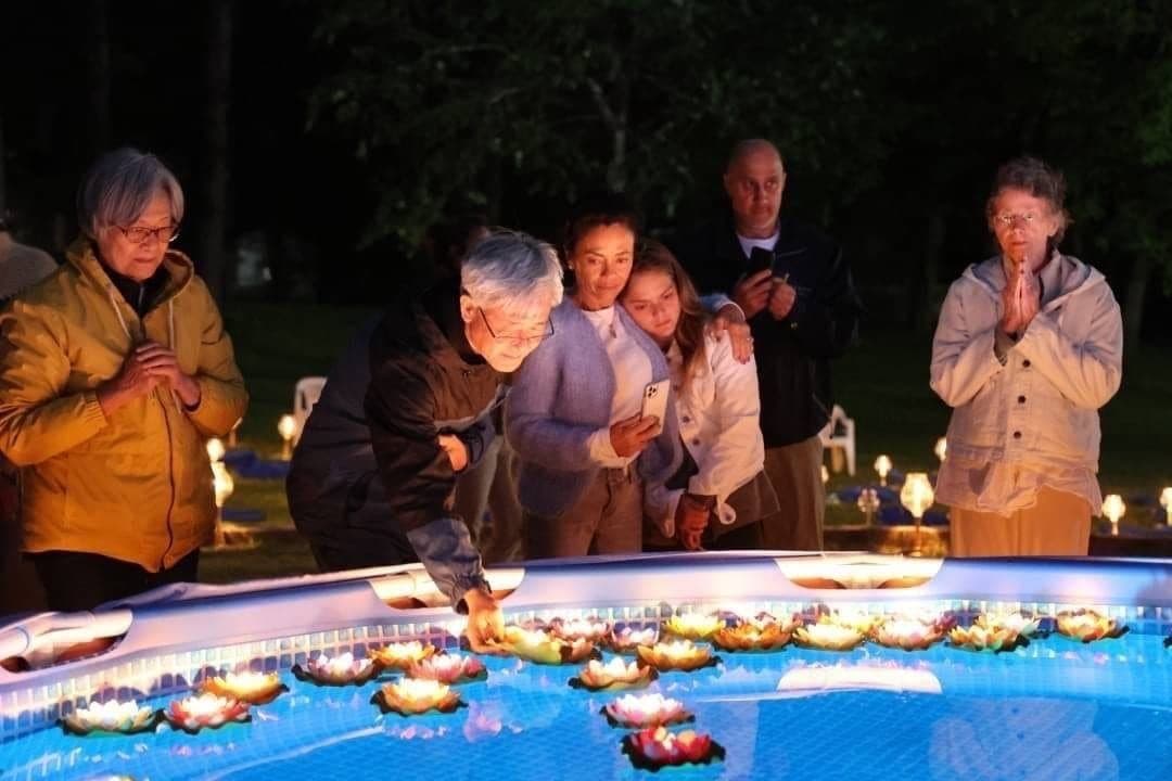 Families floating candles on water in remembrance